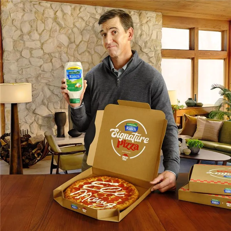 Eli Manning holding a Hidden Valley® Ranch Easy Squeeze bottle and pizza