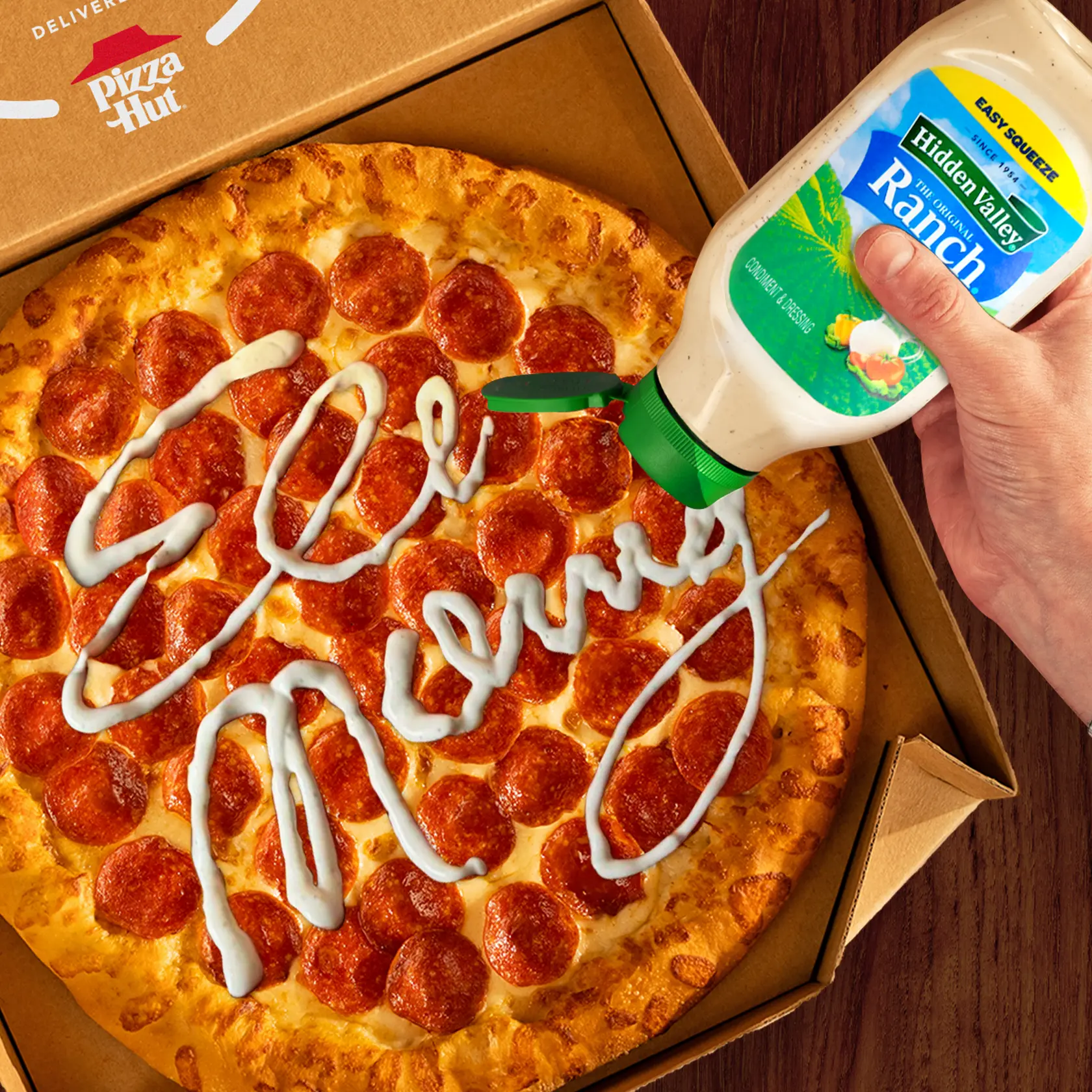 A box of pizza and a hand signing Eli Manning with a Hidden Valley® Ranch Easy Squeeze bottle