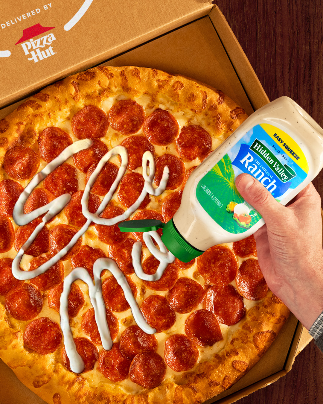 A box of pizza and a hand signing Eli Manning with a Hidden Valley® Ranch Easy Squeeze bottle